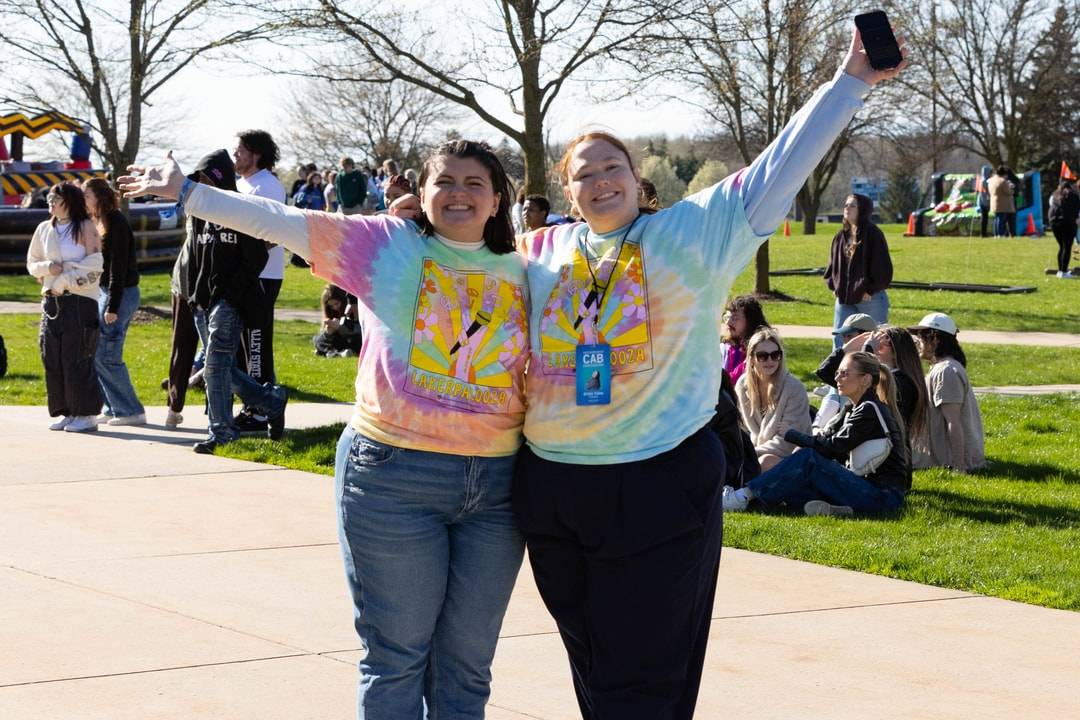 Two students smiling with their arms up